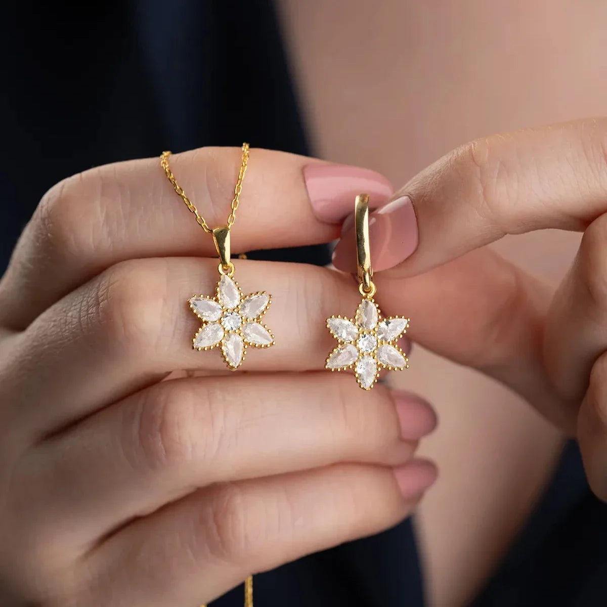 Damla taşlı lotus kolye-küpe set, elde yakın görünümü.