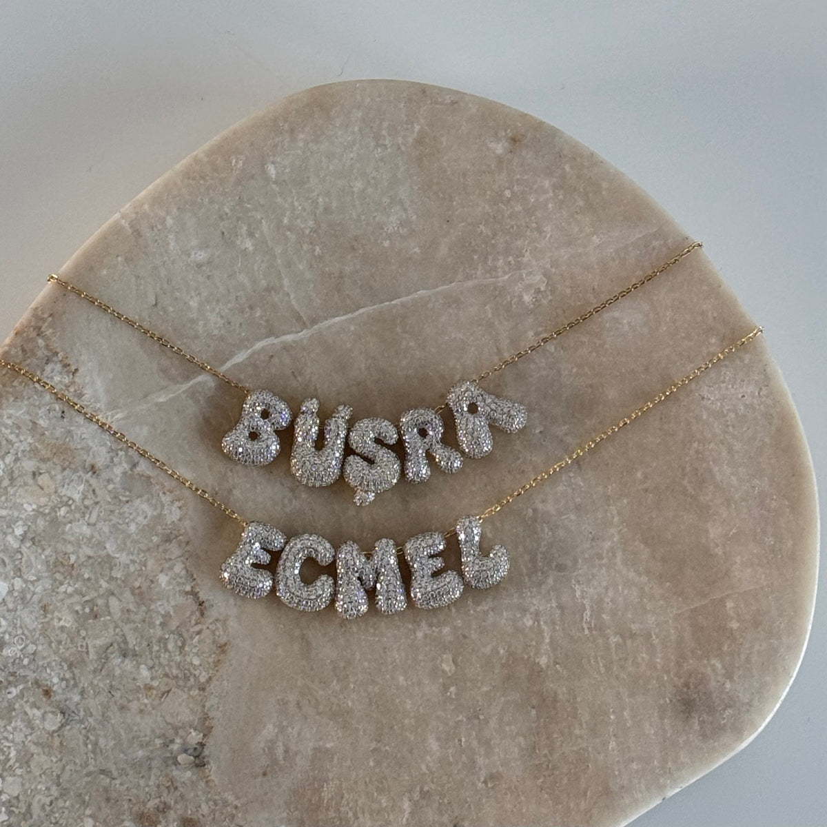 Kişiye özel isim yazılı bubble kolye, zemin üzerinde görünümü.