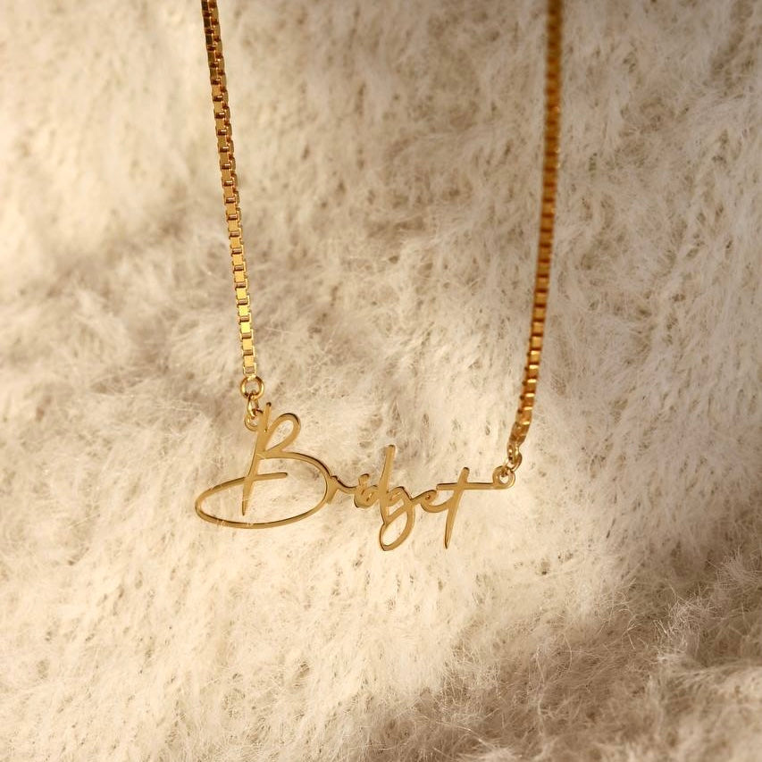 Kişiye özel isim yazılı script font küp zincir kolye, zemin üzerinde görünümü.