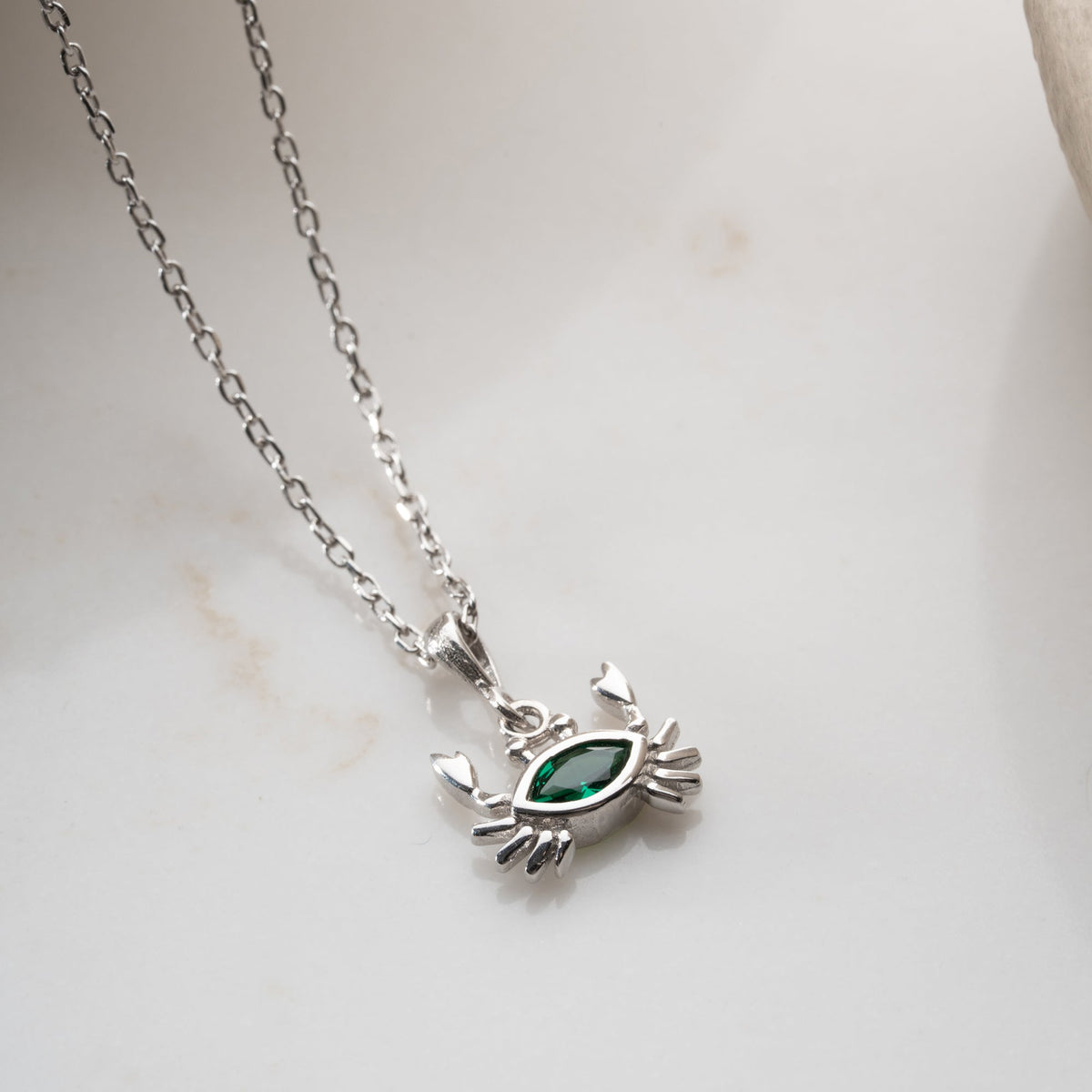 Zümrüt taşlı yengeç kolye, zemin üzerinde görünümü.