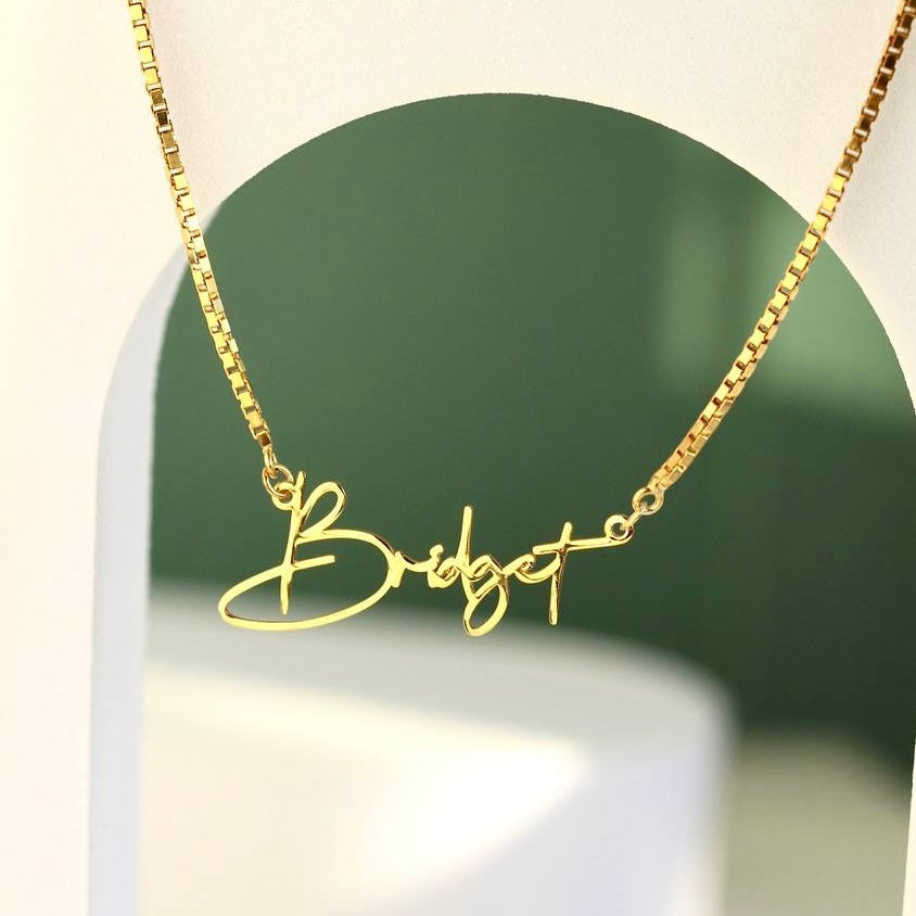 Kişiye özel isim yazılı script font küp zincir kolye, zemin üzerinde görünümü.
