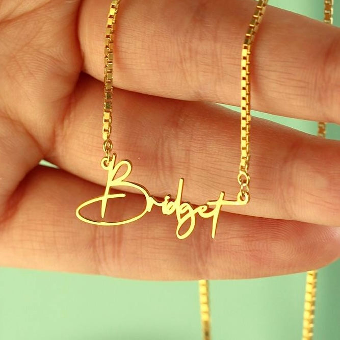Kişiye özel isim yazılı script font küp zincir kolye, elde yakın görünümü.