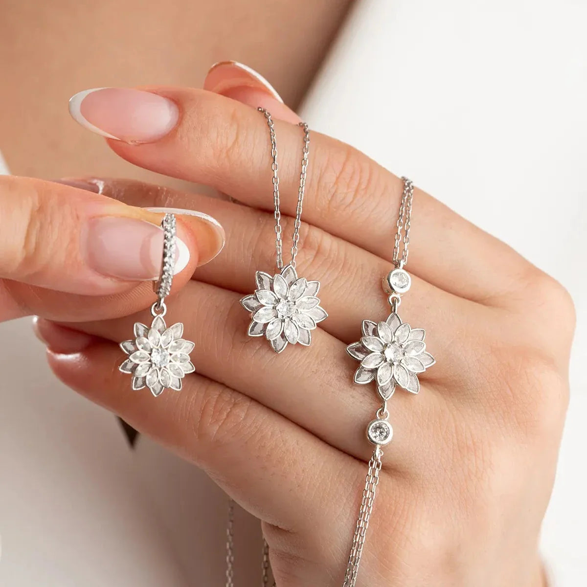 Lotus çiçeği kolye-küpe-bileklik set, elde yakın görünümü.