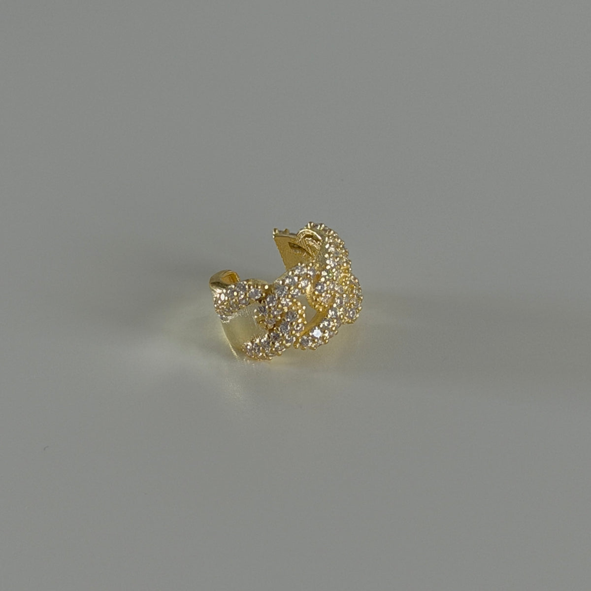 Zincir tasarımlı zirkon taşlı earcuff kıkırdak küpe, zemin üzerinde görünümü.