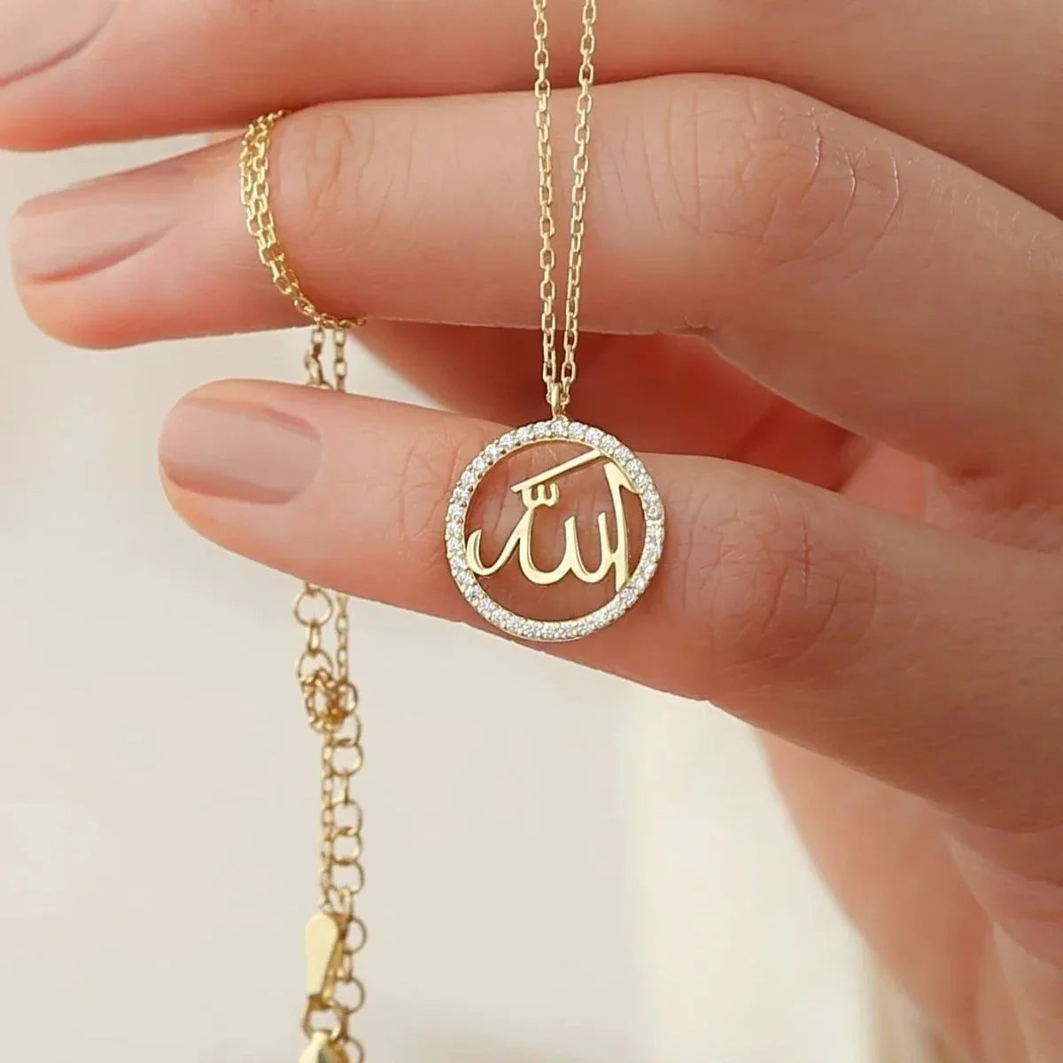 Zirkon taşlı allah lafzı kolye, elde yakın görünümü.