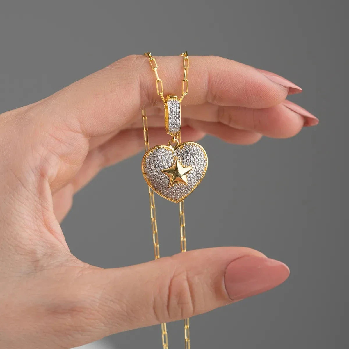 Zirkon taşlı kalp üzeri yıldızlı kolye, elde yakın görünümü.