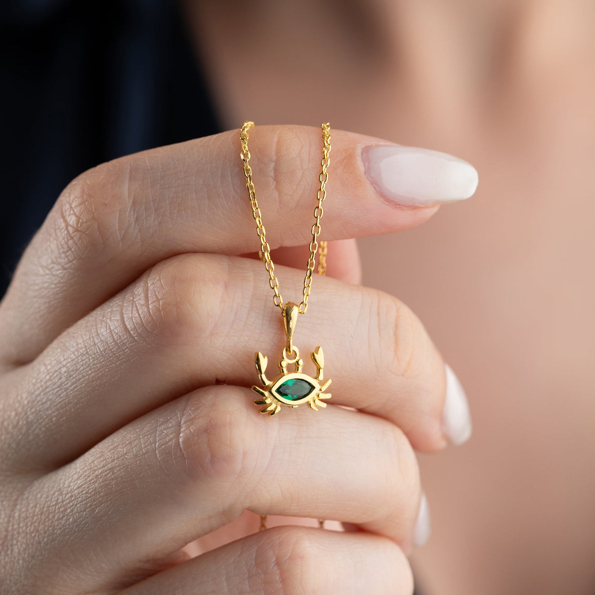 Zümrüt taşlı yengeç kolye, elde yakın görünümü.